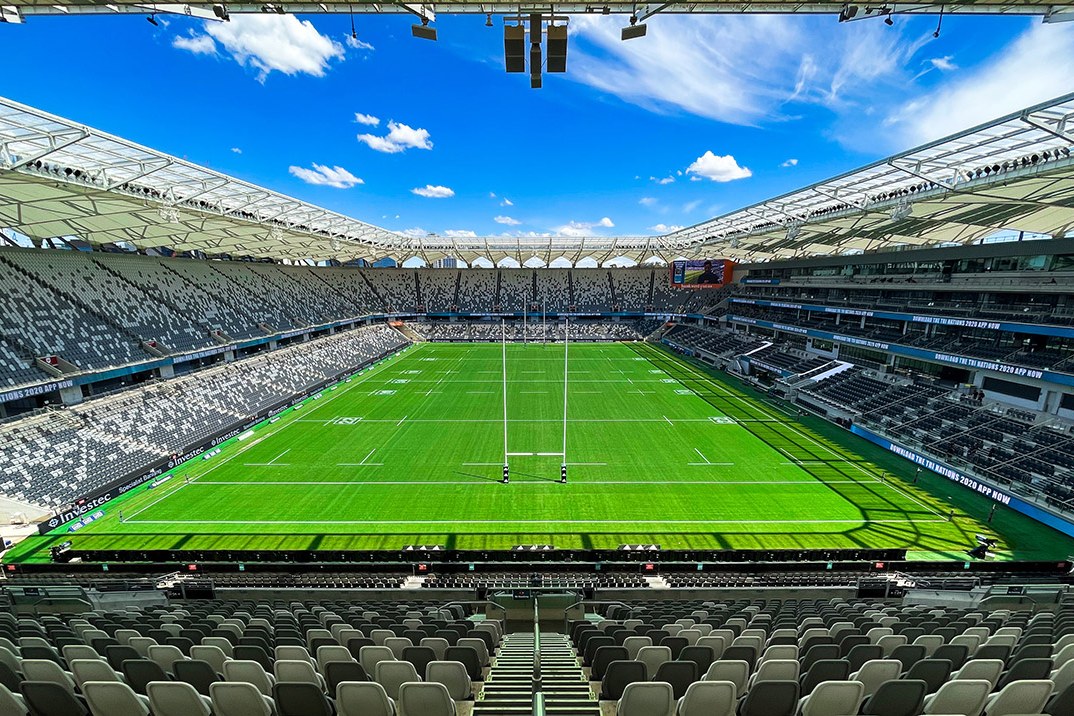 CommBank Stadium empty in bright sunshine, the full playing surface seen from high in a stand of grey and teal seats