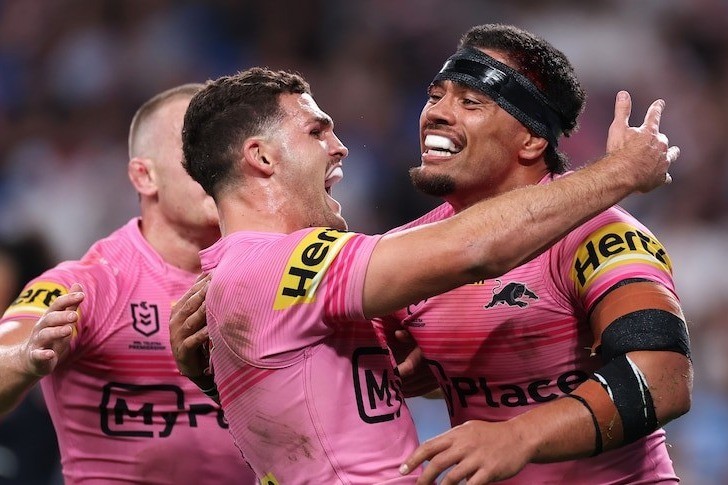 Two Penrith players in pink away jerseys embrace as they celebrate during an NRL match