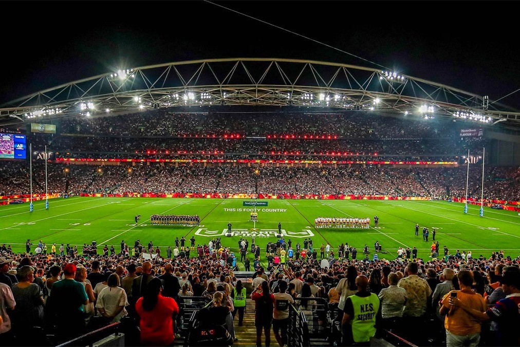 A capacity crowd fills Accor Stadium in Sydney under lights as the teams line up before kick-off