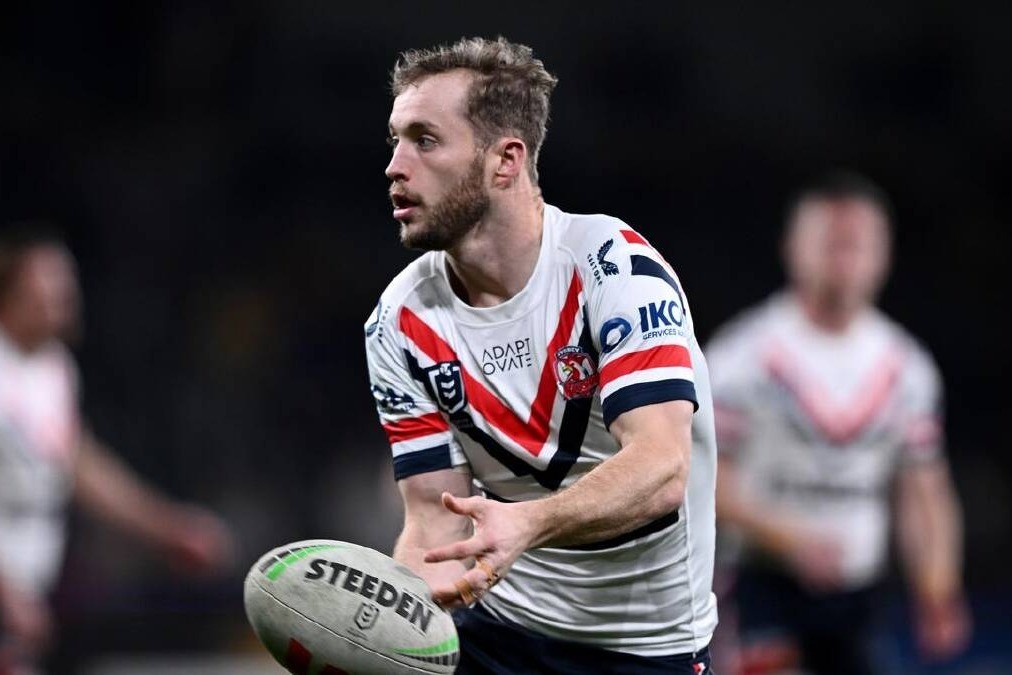 A Sydney Roosters player looks to pass the ball during an NRL match under lights